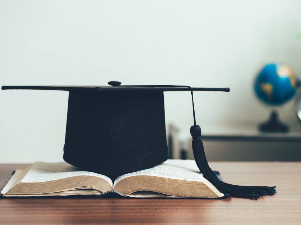Imatge de recurs. Llibres i un barret de graduat