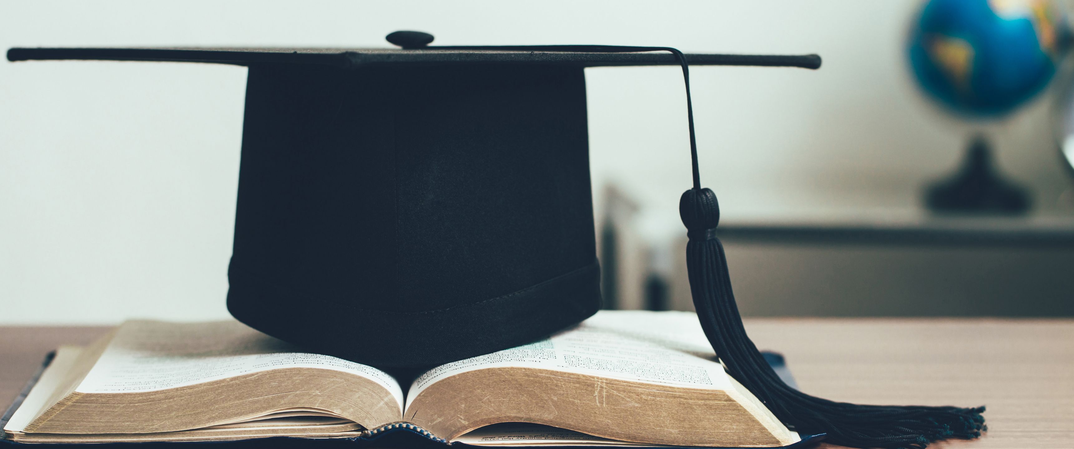 Imatge de recurs. Llibres i un barret de graduat