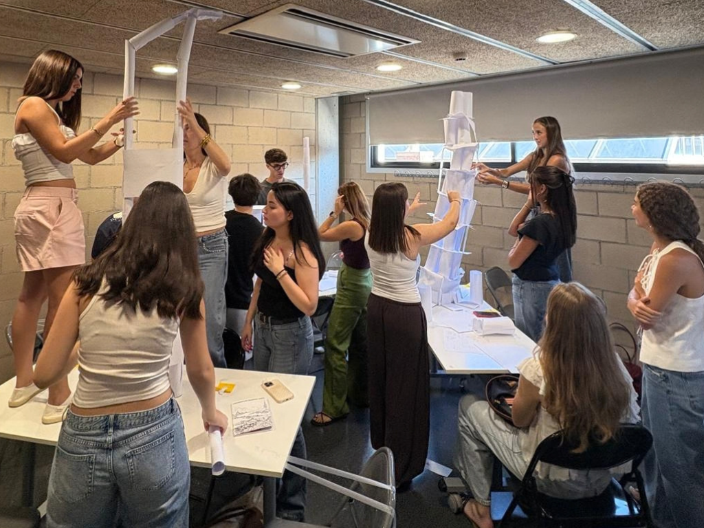 L'alumnat a l'aula, pujats a les aules, construint unes torres de paper