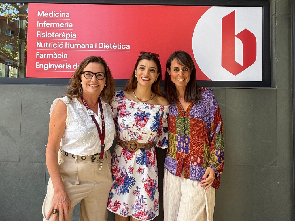 Les professores Alicia Orta i Marina Diana posant davant de la Facultat amb l'alumni Noemi Federico