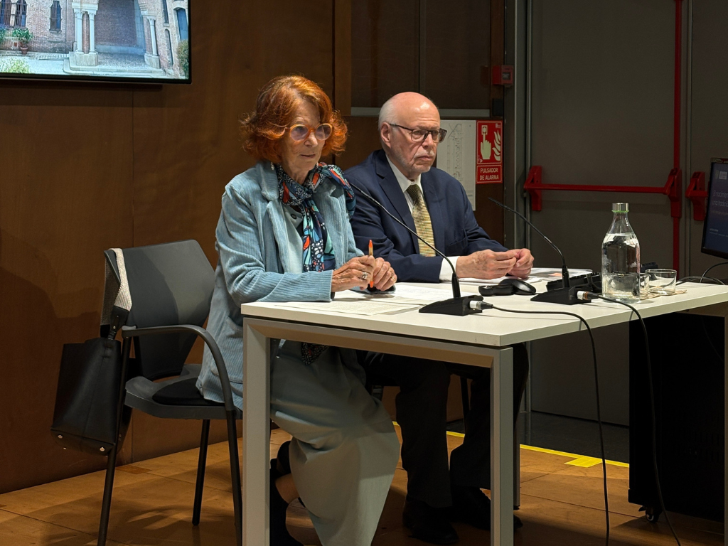 La síndica amb el Dr. Narro, asseguts a la tarima de la Facultat, parlant als micròfons de taula.