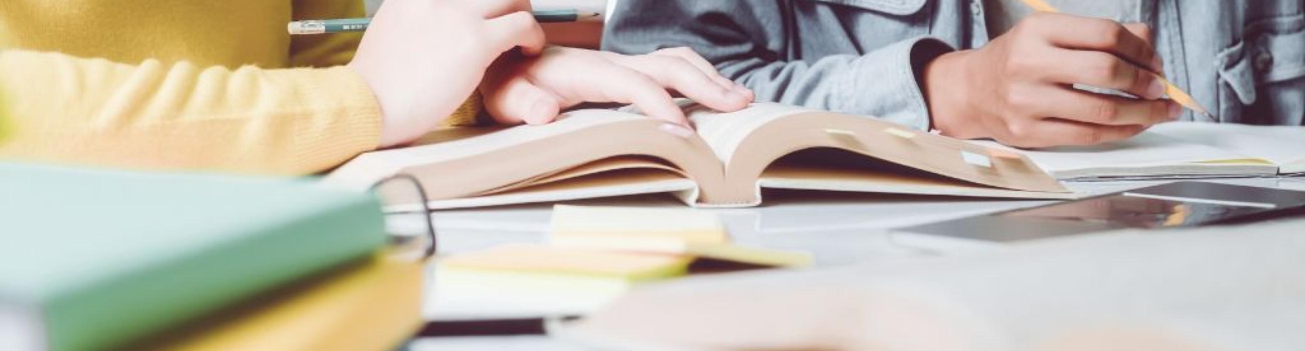 Estudiants complementant els apunts amb un llibre de text