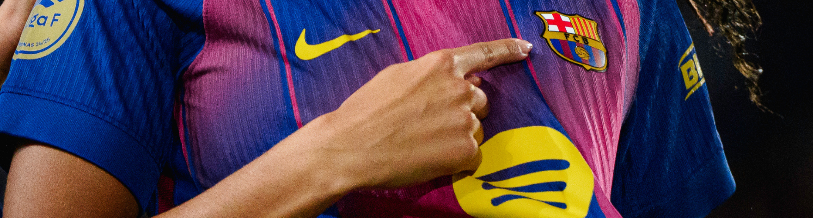 Imatge d'una jugadora del Barça assenyalant l'escut de la seva samarreta