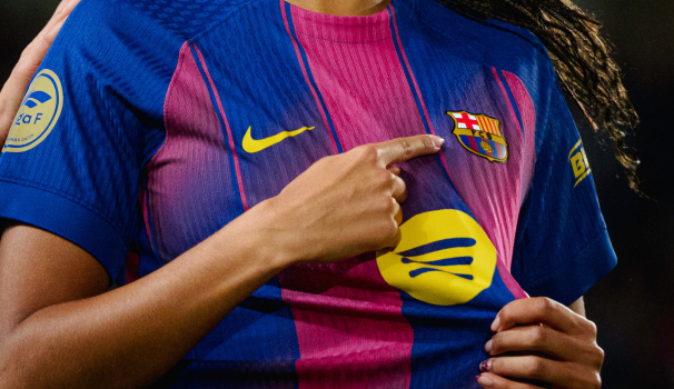 Imatge d'una jugadora del Barça assenyalant l'escut de la seva samarreta