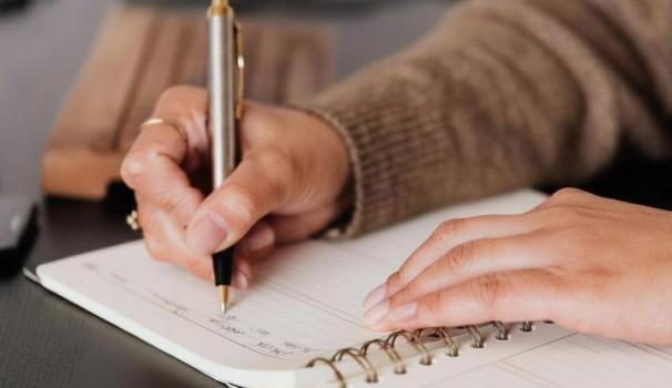 imatge de recurs d'unes mans femenines amb anells signant un document