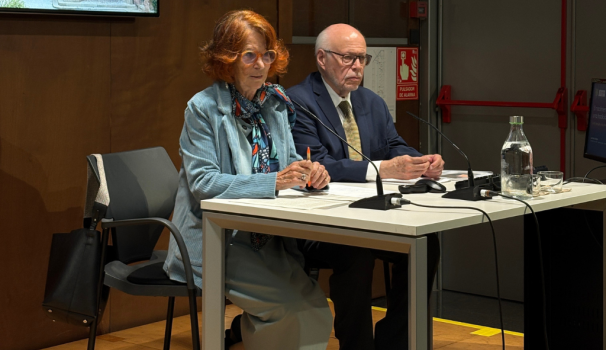 La síndica amb el Dr. Narro, asseguts a la tarima de la Facultat, parlant als micròfons de taula.